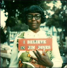 Peoples Temple member holding an "I believe in Jim Jones" sign