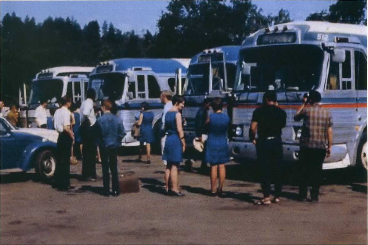 Laura and others standing in front of the fleet of greyhound-type buses