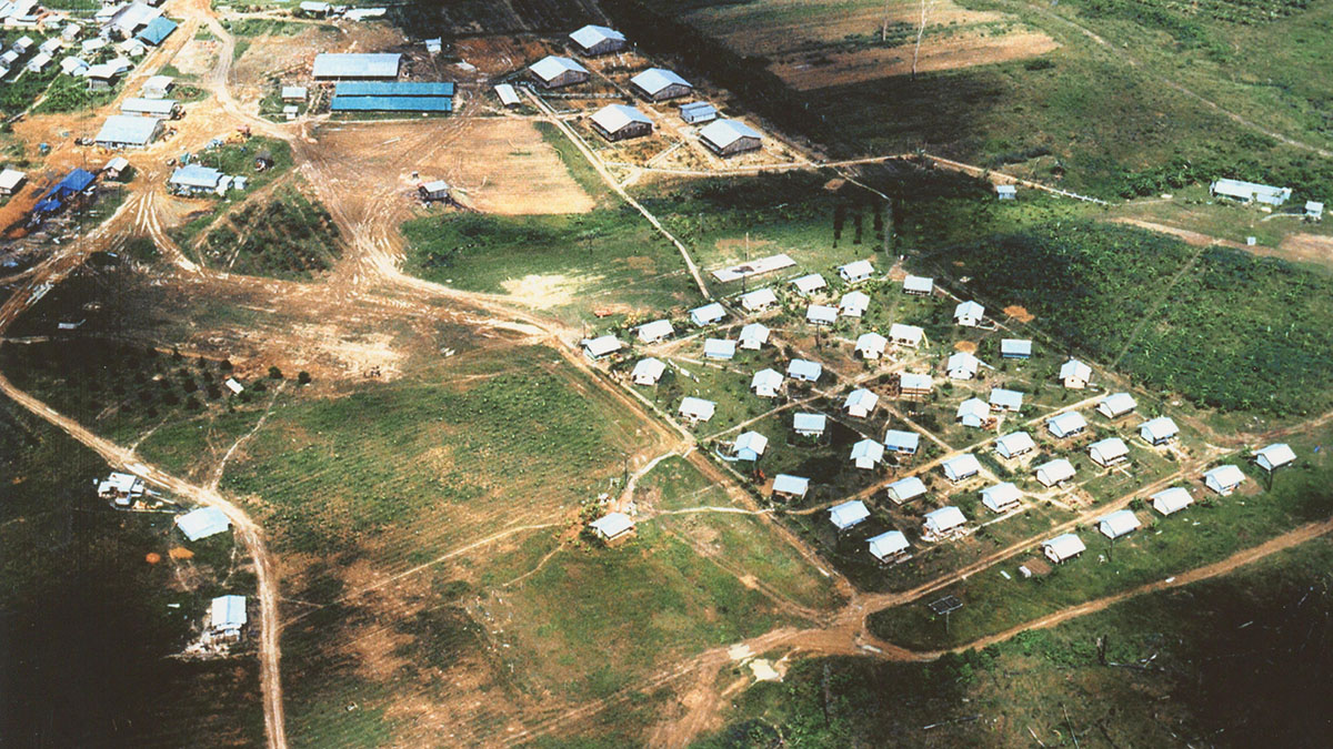 Aerial view of the Jonestown settlement in Guyana showing clusters of small white-roofed cottages, communal buildings, and surrounding farmland.